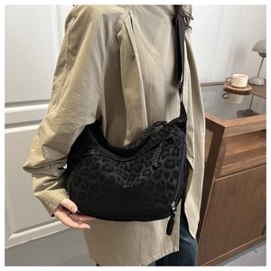 Close-up of a leopard print half-moon crossbody bag shown in a cozy home office setting