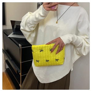 Trousse à maquillage jaune matelassée avec broderies de nœuds noirs et texture moelleuse