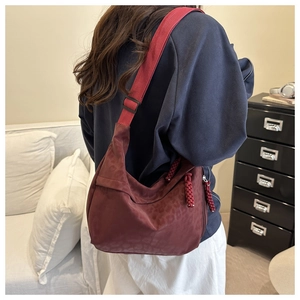 Detail of burgundy leopard print dumpling bag with adjustable strap and braided tassels
