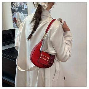 Red textured leather half-moon shoulder bag with gold metal buckle shown on model
