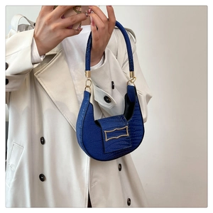 Detail of blue crescent shoulder bag with crocodile texture and gold geometric clasp