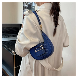 Detail of navy blue crocodile pattern faux leather half-moon bag with gold metal buckle