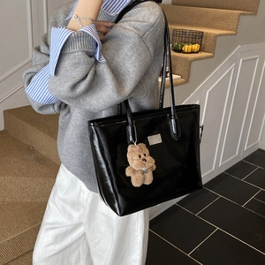 Glossy black tote bag with silver metal plate and brown plush bear charm detail