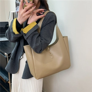 Minimalist beige leather tote bag with gold metal hook detail and spacious design