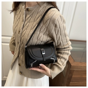 Detail of black leather underarm bag featuring silver hardware and decorative side zippers