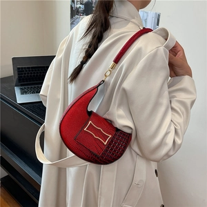 Red crocodile texture crescent shoulder bag with gold buckle on a white trench coat