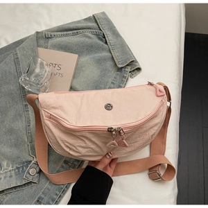 Détail du sac demi-lune rose montrant la texture matelassée et le logo métallique