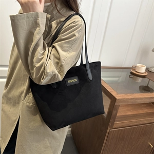 Vintage black tote bag with matte texture and gold fashion logo shown on model shoulder
