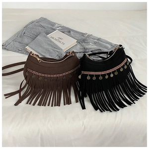 Detailansicht zweier Boho-Fransentaschen mit Vintage-Münzen auf weißem Bettzeug