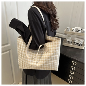 Detailed view of spacious houndstooth woven tote bag with white leather straps