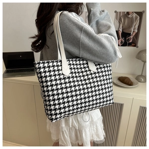 Detail of classic black and white houndstooth tote bag with white faux leather shoulder straps