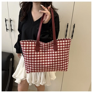 Detailed view of red houndstooth tote bag texture and high-quality leather handle