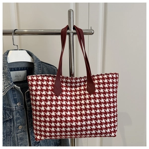 Detail of red and white houndstooth woven tote bag with slim dark red handles