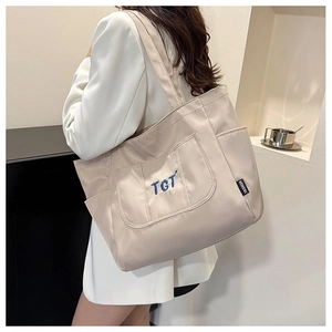 Détail du sac cabas en toile beige avec broderie TGT bleue et poches latérales pratiques