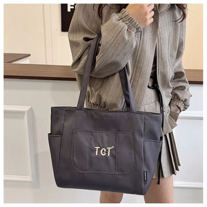 Détail de la broderie TGT et de l'étiquette FASHION sur un sac cabas gris en nylon