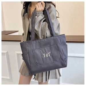 Détail du sac cabas en nylon gris foncé avec logo doré et poches latérales sur modèle