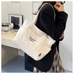 Détail du sac cabas en toile blanche avec broderie TGT bleue et étiquette mode