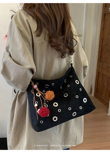 Close-up of suede tote bag with silver eyelets and colorful decorative charms