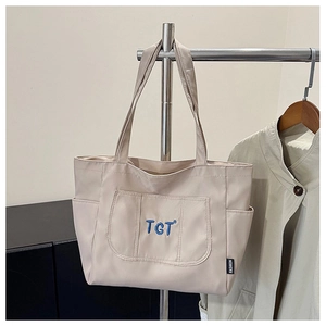 Détail du sac cabas en toile beige montrant la broderie TGT bleue et l'anse robuste