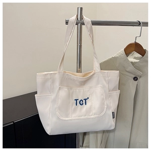 Détail du sac cabas en toile crème avec broderie TGT bleue et poches latérales