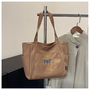Détail du sac fourre-tout en nylon marron avec broderie TGT bleue et étiquette de mode