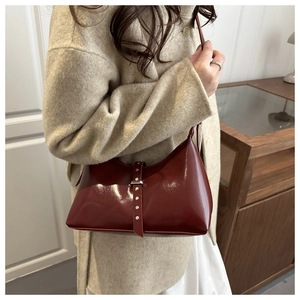 Detail of dark red patent leather shoulder bag with silver studs and belt decoration
