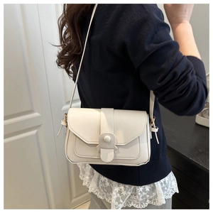 Minimalist cream leather square crossbody bag with adjustable strap shown on model