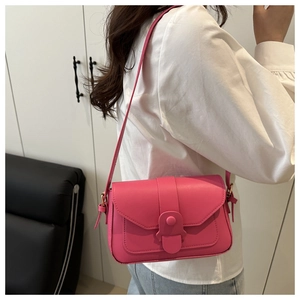 Side view of a bright rose pink leather crossbody bag worn with a white shirt and jeans