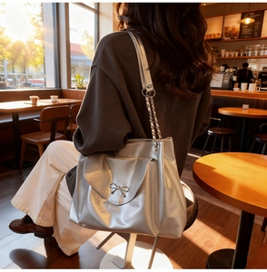 Detail of silver tote bag featuring metallic texture and bow-knot buckle in a cafe