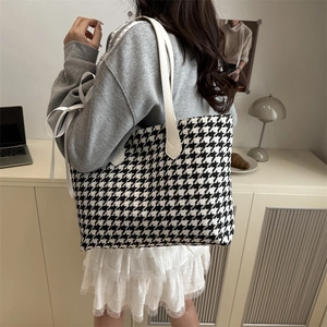 Classic houndstooth tote bag with white leather straps shown on a model in a modern room