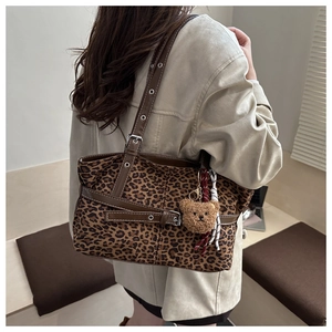 Macro detail of leopard print tote bag featuring plush bear charm and buckle straps