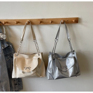 Detail of elegant tote bags with metallic bow hardware and chain strap accents
