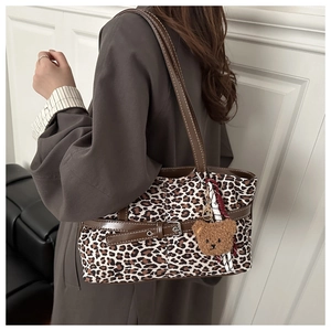 Model wearing a large leopard print suede tote bag with brown leather straps and bear charm