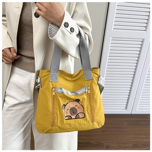 Detail of yellow tote bag with cute capybara print and functional dual zipper front pockets