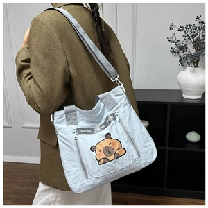 Detail view of light blue nylon crossbody bag featuring cute cartoon bear print