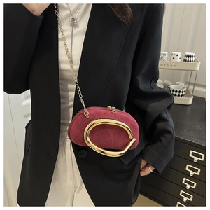 Detail of burgundy suede mini bag with unique gold geometric handle and chain strap