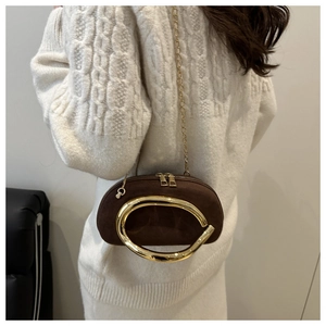 Detail of a brown suede mini box bag with a large gold metal handle and chain strap