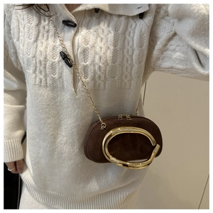 Detailed view of dark brown suede clutch featuring a large gold ring and chain strap