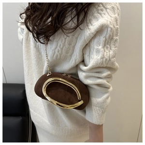 Detailed view of brown suede mini bag with gold circular handle and chain strap