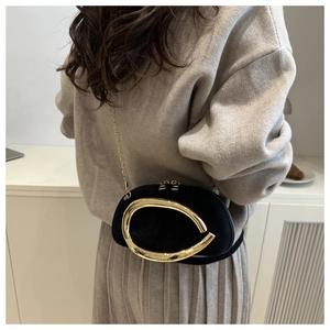 Detail of mini black velvet clutch with large oval gold buckle and gold chain strap