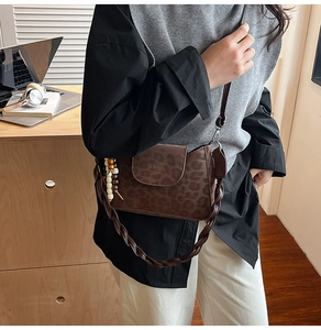 Close-up of leopard print crossbody bag with braided strap and beaded charm details