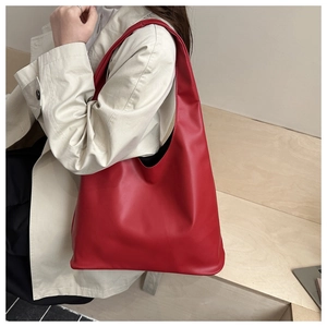 Detail view of large red soft PU leather hobo bag worn with a stylish beige coat