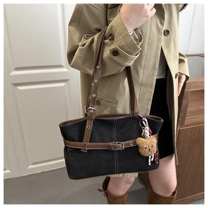 Dettaglio della borsa tote vintage in tela nera con finiture in pelle e ciondolo orso