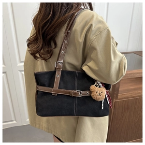 Detail of suede shoulder bag with leather buckle, teddy charm and striped scarf accent