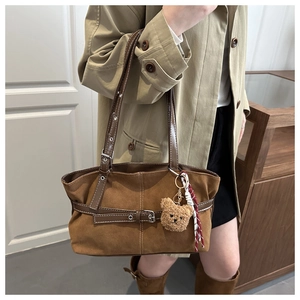 Dettaglio della borsa tote vintage in pelle scamosciata marrone con orsetto di peluche