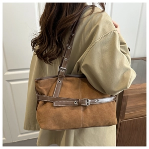 Detail of vintage brown suede shoulder bag with silver metal buckle and adjustable strap