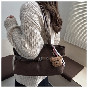 Detail of vintage brown suede tote bag with plush bear charm and leather strap