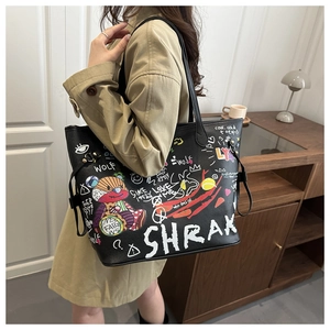 Detailed view of black tote bag with colorful bear graffiti and leather texture on a model