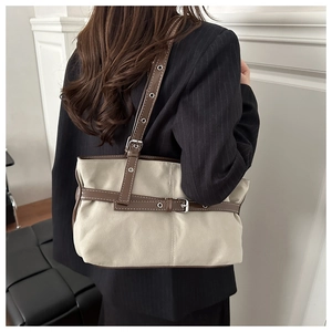 Detail of canvas tote bag with brown leather strap and silver metal eyelets for office wear