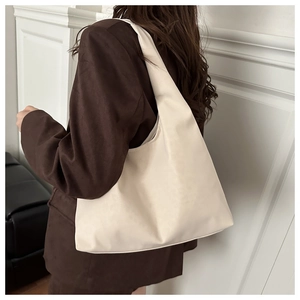 Fashionable creamy white oversized faux leather tote bag shown on a model's shoulder